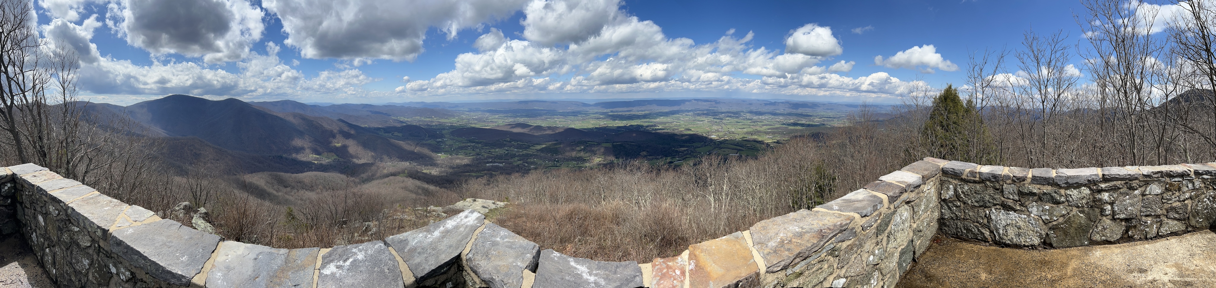 A panoramic photo showing a wall that is very distorted, and a stunning landscape behind it.